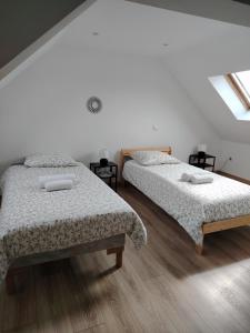 two beds in a room with white walls and wooden floors at Chez Albert au bord de plage in Cherrueix