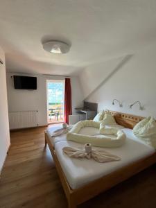 a bedroom with a large bed with white sheets at Pension Neuhof in Ossiach