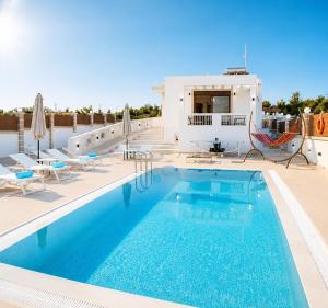 a swimming pool with chairs and a house at Luxury Villa John in Panormos Rethymno