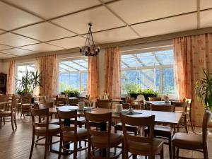 a dining room with tables and chairs and windows at Pension Neuhof in Ossiach