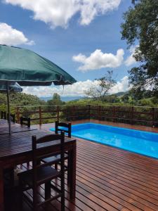 a wooden deck with a pool and an umbrella at Sitio Tahiupara in Gonçalves