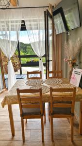 a dining room table with two chairs and a window at Domek na Folwarku z jacuzzi in Tarnawa Dolna