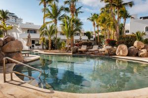 a large swimming pool with palm trees and a building at Hotel & Suites El Moro in La Paz