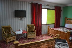 a bedroom with a bed and two chairs and a television at Pine Hills, Naran in Naran +50 photos