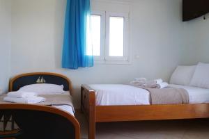 two beds in a room with a window and blue curtains at Beach Residence Walk to Beach Garden - Parking in Chalkida