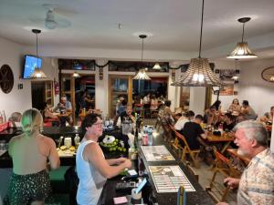 a group of people sitting at a bar in a restaurant at Pousada Guarujá, suítes Praia do tombo in Guarujá