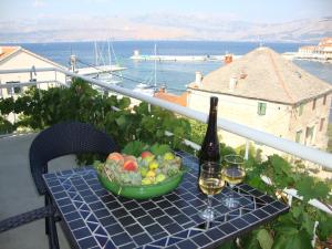 ein Tisch mit einer Schale Obst und einer Flasche Wein in der Unterkunft Apartments Romana in Postira