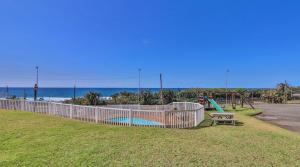 a park with a playground and a bench and the ocean at Scottburgh Views 707 Seafront Apartment in Scottburgh