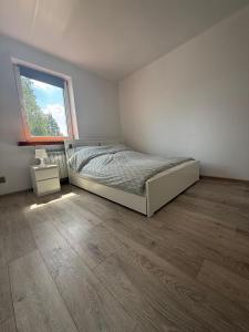 a white bedroom with a bed and a window at Wenecja Apartment in Wadowice