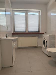a bathroom with a sink and a washing machine at Wenecja Apartment in Wadowice