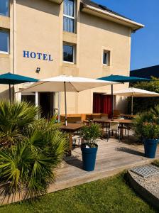 a hotel with tables and umbrellas in front of it at Eurocéan Adonis Budget in Guérande