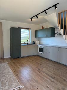 a large kitchen with white cabinets and a wooden floor at Tavo Jūros Namai in Palanga