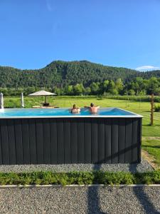 two people are sitting in a swimming pool at Drau Lodge in Wernberg