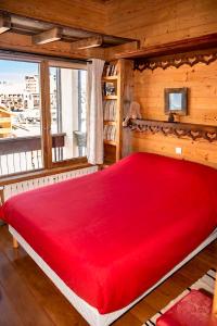 a large red bed in a room with a window at Tignes duplex luxe parking 6-8 p in Tignes