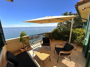 a patio with chairs and an umbrella and the ocean at Villa Tergeste in Trieste