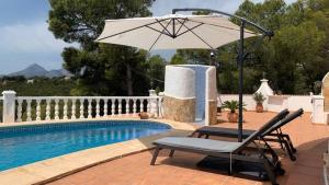 a chair and an umbrella next to a swimming pool at Traumhaftes Apartment mit Pool in Altea