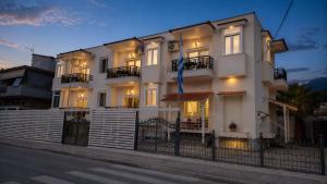 a white building with a blue flag in front of it at Studios Chrissi-Renovated 2026, Just 20m from the Beach in Skala Sotiros
