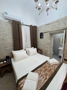 a bedroom with a large bed and a chandelier at Turkman Madrasah XIX Century Hotel in Bukhara