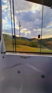 a window with a view of a field and a pole at Chalé Vista do Paraíso in Gonçalves +34 photos