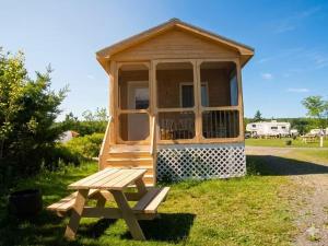 a wooden cabin with a picnic table and a bench at Bras D'Or Lakes Campground in Baddeck Inlet +1 photo