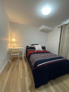 a bedroom with a bed and a table with a lamp at Cosy and Cute Private Basement Suite in Winnipeg