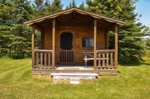 a small wooden cabin in a field of grass at Bras D'Or Lakes Campground in Baddeck Inlet