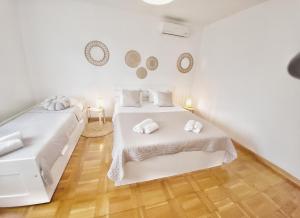 two beds in a room with white walls and wooden floors at Villa Marante with heated private pool in Podstrana +61 photos