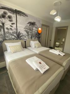 two beds in a room with palm trees on the wall at Olive House in Pamukkale