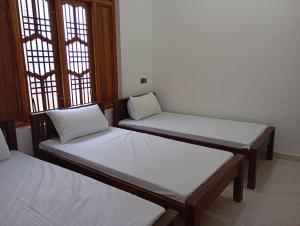 three beds sitting in a room with windows at East villa in Kalmunai