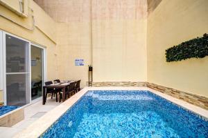 a swimming pool in the middle of a room with a table at Modern Duplex Apartment with Private Pool & AC Central Malta in Balzan