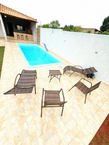 a swimming pool with two lawn chairs and a swimming pool at Chácara Recanto gramado in Tatuí