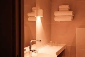 a bathroom with a sink and a mirror and towels at Logis Hôtel et Restaurant La Pension du Moulin in Pont-Aven +63 photos
