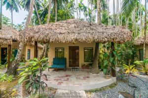 a house with a thatched roof and a blue chair at Munjoh Ocean Resort - Private Beachfront Luxury Retreat in Havelock in Havelock Island