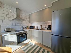 a kitchen with white cabinets and a stainless steel refrigerator at Lönngården in Kristinestad +32 photos