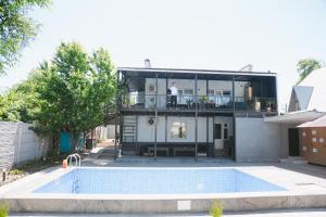 a man standing on the balcony of a house with a pool at Apple Hostel Bishkek in Bishkek