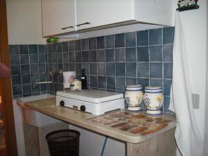 a kitchen counter with a white toaster and blue tiles at Dammuso Bouganville in Scicli