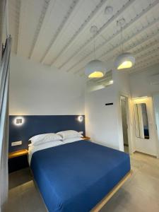 a blue bed in a white room with two lights at Gemelos Cozy Stay in Megali Ammos