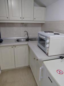 a white kitchen with a microwave and a sink at Neptune Resort in Kavos