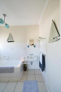 een witte badkamer met een bad en een wastafel bij Tulbagh Travelers Lodge - Cape Dutch Quarters in Tulbagh