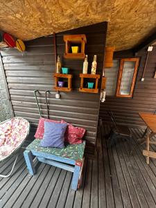 a bench on a deck with a table and shelves at Hostal Palguin 261 in Pucón