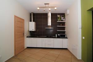 uma cozinha com armários brancos e uma parede preta em Palanga Apartaments - Mickevičiaus 8 em Palanga