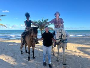 a man and two women riding horses on the beach at Hotel Pousada Cachalote in Coruripe