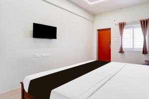 a bedroom with a bed and a tv on the wall at Collection O Karumathampatti in Coimbatore