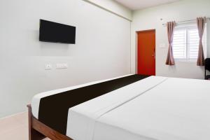 a bedroom with a bed and a tv on the wall at Collection O Karumathampatti in Coimbatore