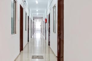 an empty hallway with white walls and wooden doors at Super Hotel O Okkilipalayam in Coimbatore