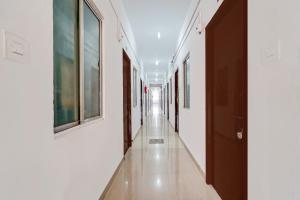 a hallway with white walls and a long hallway with wooden doors at Super Hotel O Okkilipalayam in Coimbatore +32 photos