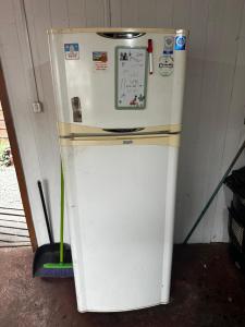 a white refrigerator in a room with a broom at Hostal Palguin 261 in Pucón