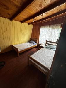 an attic room with two beds and a window at Hostal Palguin 261 in Pucón