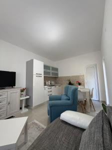 a living room with two blue chairs and a kitchen at B&B Ana in Virpazar