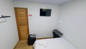 a bedroom with a bed and a television on the wall at Hotel Luxx Sorriso in Sorriso